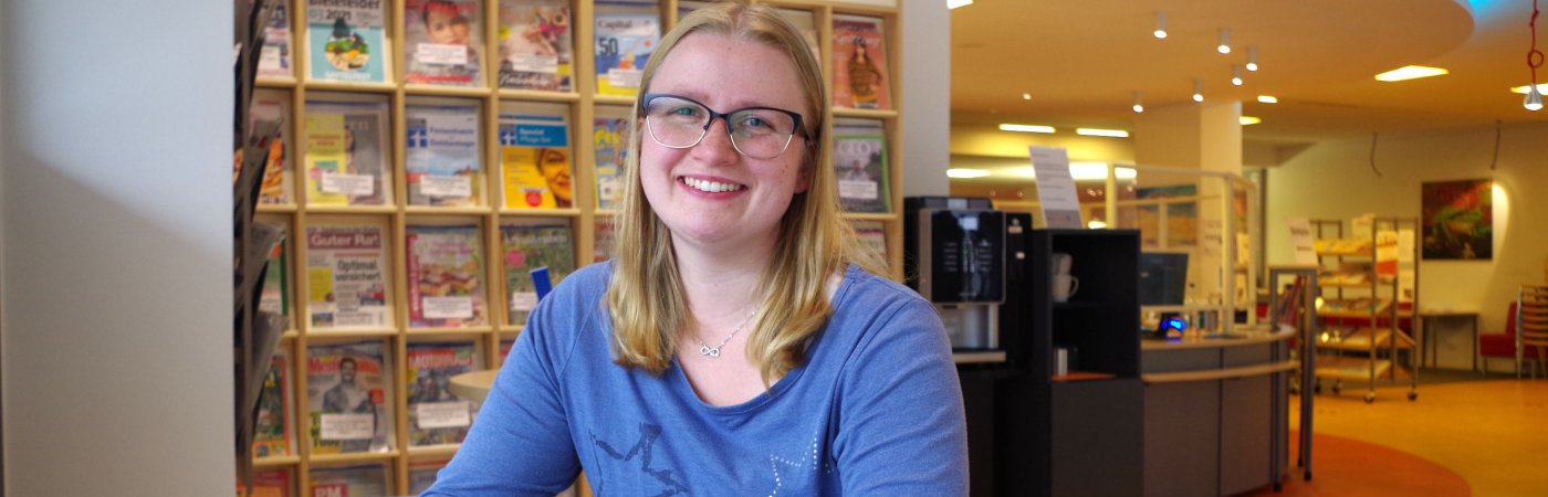 Gezeigt wird eine in die Kamera lächelnde junge Frau