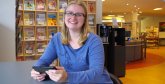 Mitarbeiterin steht an einem Bücherregal