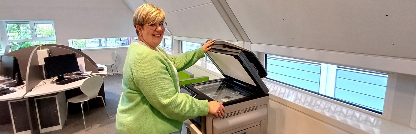 Eine Mitarbeiterin steht vor einem Kopierer