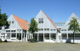 Zu sehen ist von außen das Stadthaus in Wiedenbrück, ein weißes Gebäude mit drei Giebeln, rotem Dach und vielen Fenstern, davor der zwei belaubte Bäume