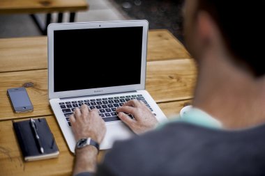 Gezeigt wird ein vor einem Laptop sitzender Mann