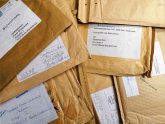 Mehrere große, braune Briefumschläge liegen unsortiert nebeneinander