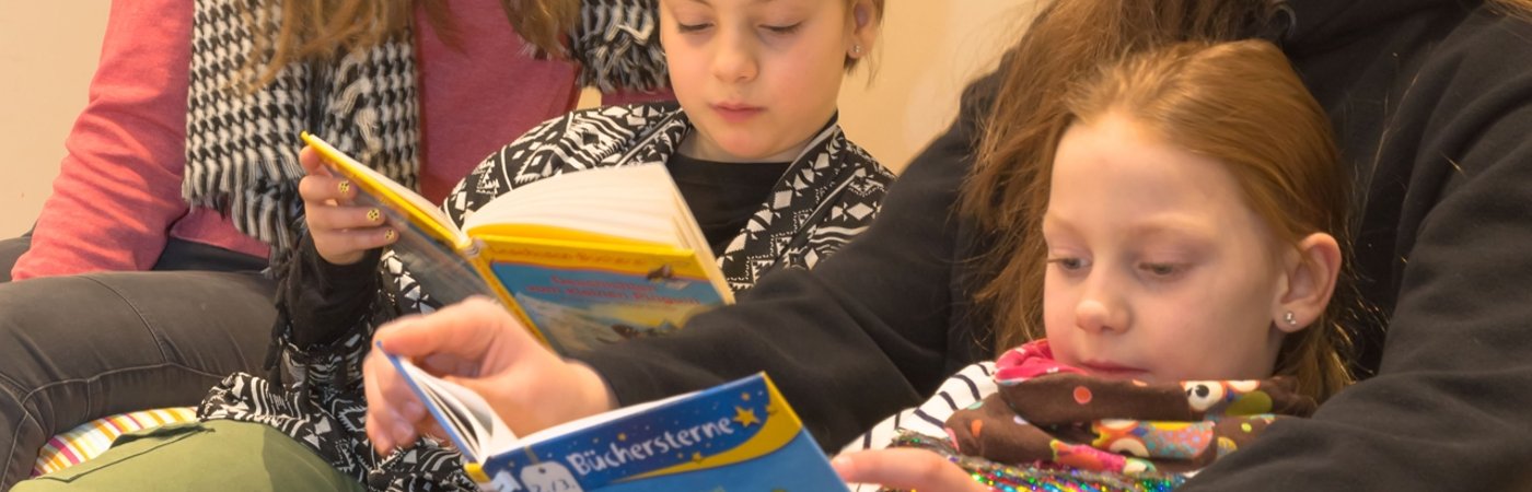 Kinder und Jugendliche sitzen zusammen und lesen