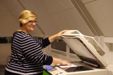 Eine Kundin steht am Kopierer und lächelt in die Kamera