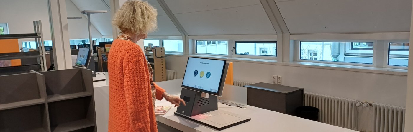 Gezeigt wird eine Mitarbeiterin an den Selbstverbuchern