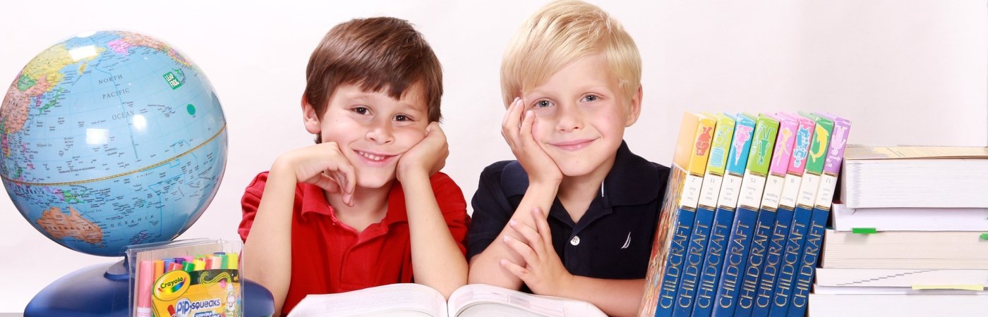 Gezeigt werden zwei Jungs zwischen Laptop und Globus