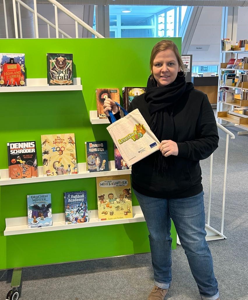 Gezeigt wird eine Mitarbeiterin, eineLesestart-Tasche  in der Hand haltend