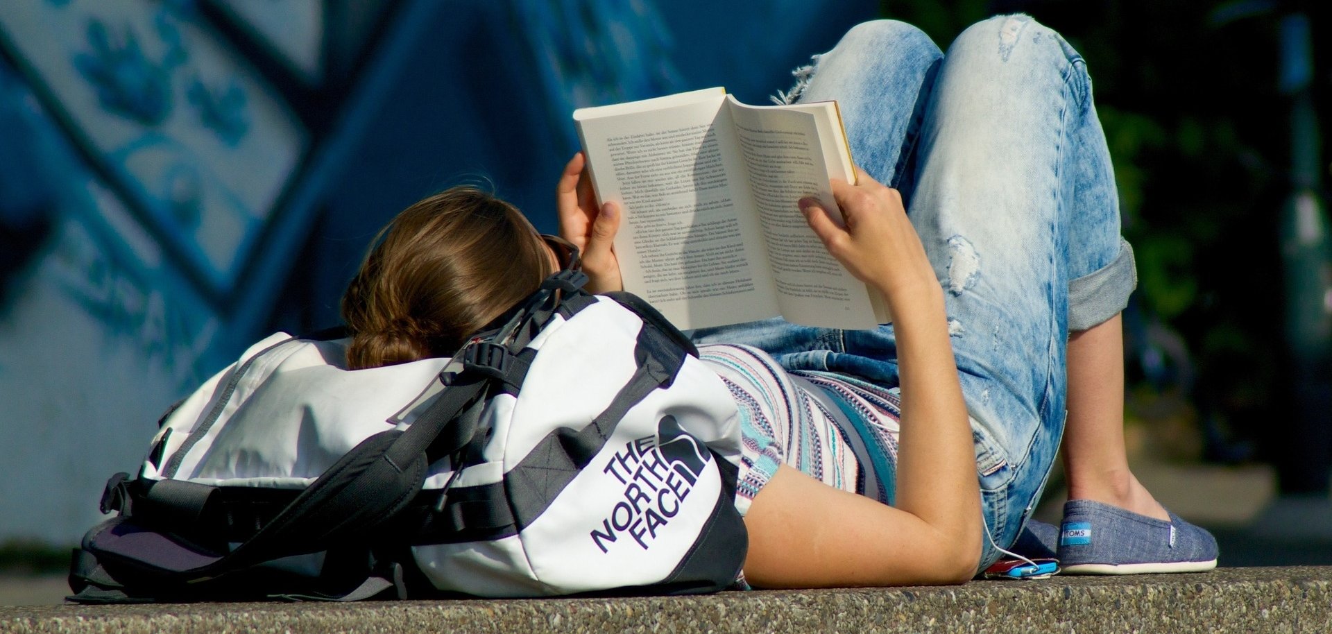 Lesende Frau Eine Mitarbeiterin sitzt an einem Tisch und umarmt einen vor ihr liegenden Stapel Bücher