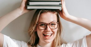 Eine junge Frau hält ein Buch über ihren Kopf