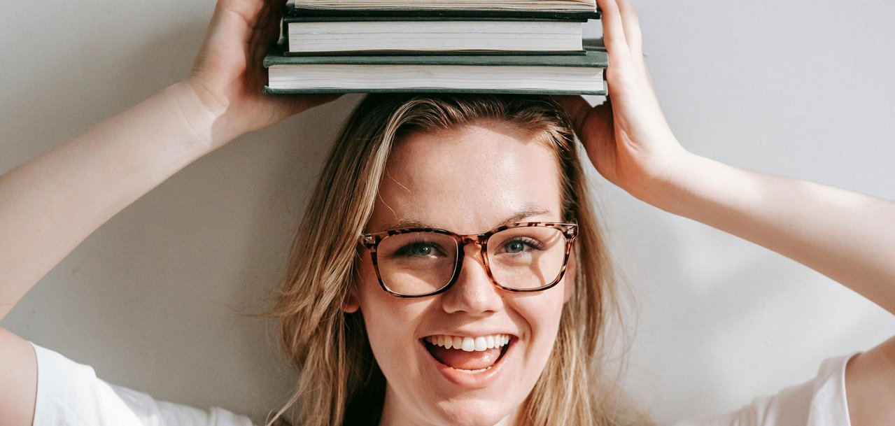 Gzeigt wird eine junge Frau, ein Buch über den Kopf haltend