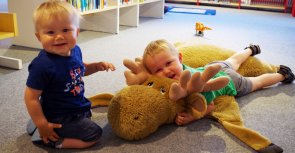 Zwei Kinder liegen auf einem Stofftier