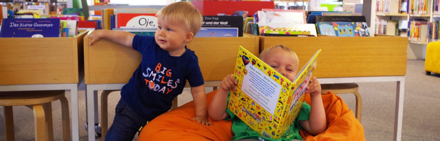 Gezeigt werden zwei Kinder vor dem Bilderbuchtrog