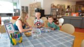 Eine Mutter sitzt mit ihren Kindern an einem Tisch und bastelt