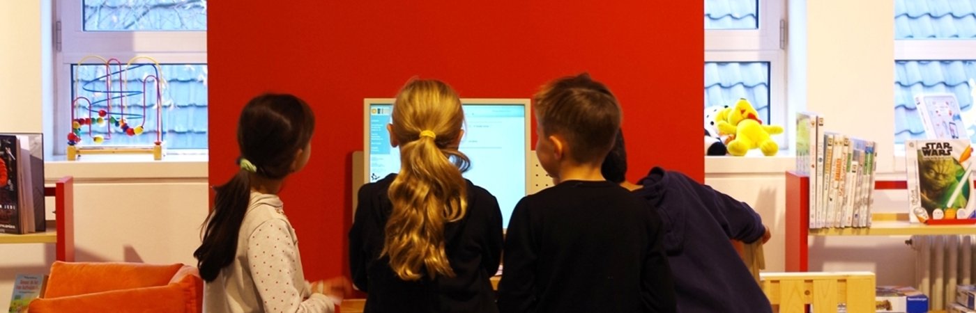 Gezeigt werden Kinder, vor einem PC stehend