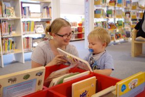 Gezeigt wird eine Mutter, die ihrem Kind vorliest