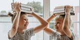zwei Kinder halten sich Bücher über den Kopf