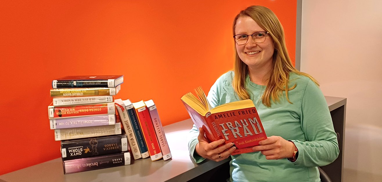 Gezeigt wird eine Mitarbeiterin mit einem Buch in der Hand