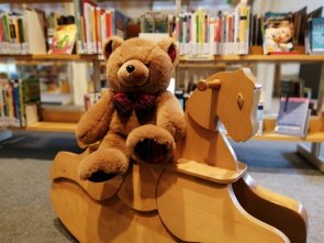 Teddy auf Schaukelpferd Ein Teddy sitzt auf einem Holzschaukelpferd