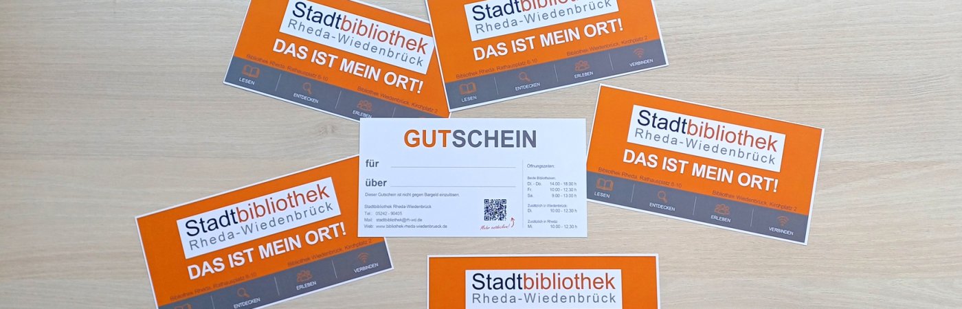 orangefarbene Gutschein der Stadtbibliothek liegen auf einem Tisch