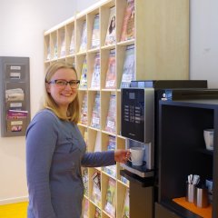 Eine Kundin steht am Kaffeeautomaten in der Bibliothek in Rheda